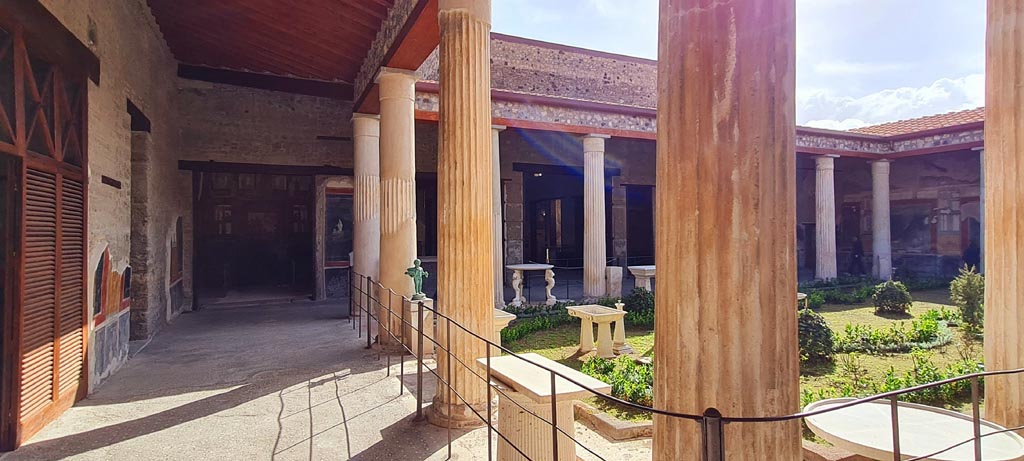 VI.15.1 Pompeii. April 2023. Looking east along north portico. Photo courtesy of Giuseppe Ciaramella.
The “Cupid’s room” (PPM – room q) is on the left, and the Exedra in north-east corner, (PPM – room p) is centre left. 
