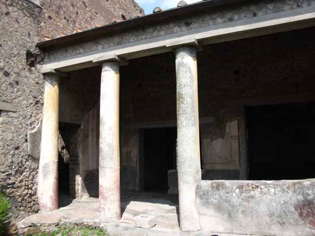 VI.15.8 Pompeii. May 2010. Looking north-east from garden towards portico. Doorways to atrium, room leading to VI.15.7 and doorway to oecus.  According to Jashemski, the peristyle garden to the left of the atrium originally had a portico on the east side. It was supported by five stucco-covered brick columns, two of which were engaged, yellow above, red below. Of the four spaces between the columns, two were later left open; the third was closed by a low masonry wall. The fourth was incorporated into the west wall of the small room built to the south of the portico. See Jashemski, W. F., 1993. The Gardens of Pompeii, Volume II: Appendices. New York: Caratzas. (p.157)
