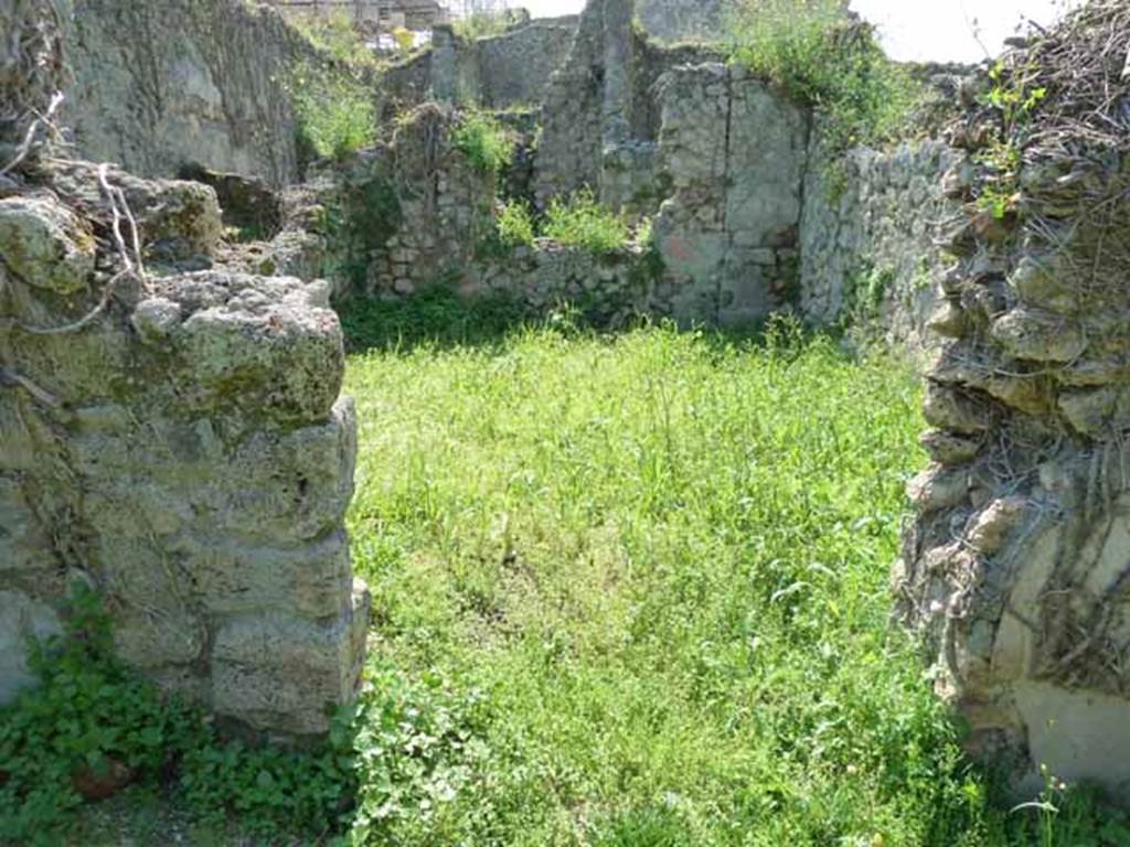 VI.16.11 Pompeii. May 2010. Doorway to rear room in north-west corner of shop. Looking west. According to NdS, the doorway would have had doorjambs and a threshold of wood.
The floor was made of opus signinum but was poorly preserved. The walls were divided into large red panels, divided by yellow pilasters or fillets, with feeding birds in the middle, a flying swan, and a rectangular painting with faded representation. The dado was red but also badly preserved. The frieze had a white background. The remains of the white frieze were still visible upon excavation, in the height of the west wall, in which there was a window. See Notizie degli Scavi di Antichit, 1908, p. 59.
