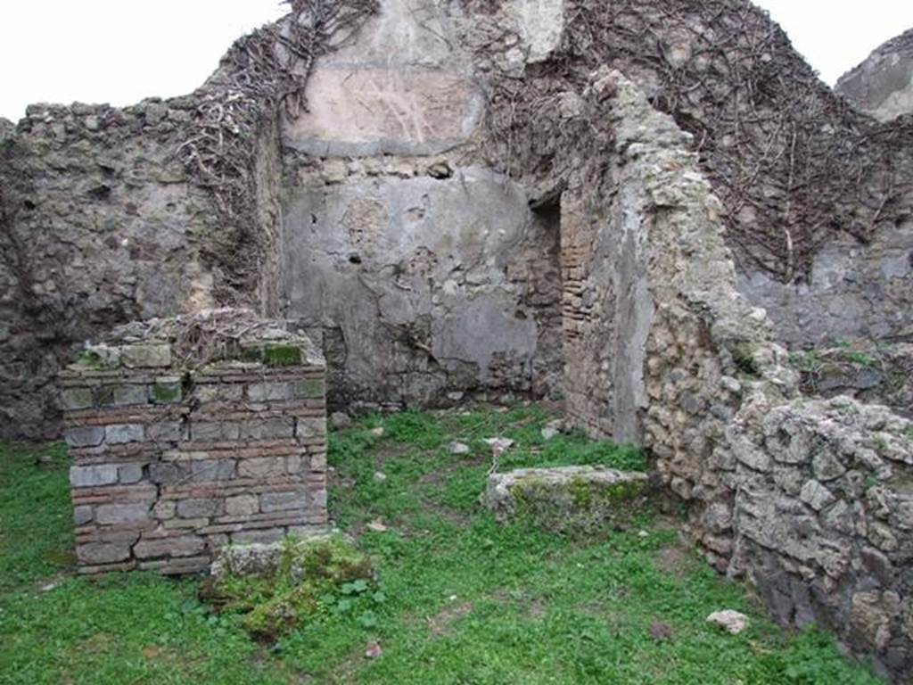 VI.16.18 Pompeii. December 2007. Doorway to rear room in centre, with doorway to rear room on north side. According to NdS, this room contained a limestone boulder that was used to form the first rung of a wooden staircase to the upper floor.  The walls of the room were bare and unpainted and the floor was of opus signinum. In the heights of the north and west walls could be seen the white plaster of the upper room. A small doorway, with large threshold made of pieces of lava, at the left end of the north wall led into a small room.
