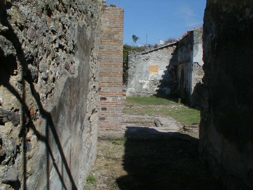 VI.16.26 Pompeii. September 2004. Looking east from entrance corridor A, across to atrium B.
According to NdS, the floor of the atrium was of cocciopesto.
The walls of the atrium had a high plastered dado (intonaco laterizio) and above this was a white plaster.
There was an impluvium in the centre and a large portico supported by a double pilaster and columns.
In the north-west corner of the impluvium was the pilaster to support the roof of the portico, and in the south-west corner was one of the two columns. 
The other column was not far from the north-east corner of the impluvium.
The pilaster was made of rows of bricks and cut tufa in the manner of bricks.
The remains of the column to the west were all brick, while the other was made of brick and limestone.
See Notizie degli Scavi di Antichità, 1908, (p.183-192).
