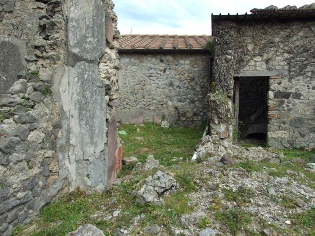 VI.16.29 Pompeii. March 2009. Doorway to room H, triclinium, in north-east corner of atrium.  In front of the two doorways, the rubble would have been the site of the east wall of the atrium.
According to NdS, in the east wall of the atrium was a large window, with a doorway on either side of it. The doorway on the north opened into rectangular room H.
The floor was of cocciopesto. In the right end of the south wall of room H was a doorway that led into the area behind the window, room I. From room I, the other doorway on the south side of the window led back into the atrium.
According to Giacobello, the doorway and wall on the east side of the atrium containing two niches collapsed following the 1980 earthquake. Today, of the two arched niches only the one on the left has been partially conserved. They would have been a short distance away from each other, and plastered inside in white stucco. See Giacobello, F., 2008. Larari Pompeiani: Iconografia e culto dei Lari in ambito domestico.  Milano: LED Edizioni. (p.243)