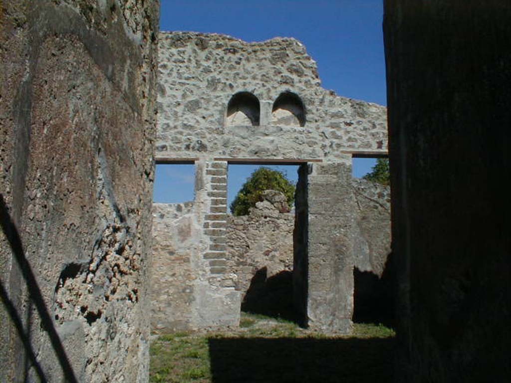 VI.16.32 Pompeii. September 2004. Room B, looking east from entrance fauces across atrium.
When discovered the walls of the atrium were rustic and the only decoration was a high dado (laterizio).
In the high eastern wall were two semi-circular niches, the portion of wall around them was faced with white plaster forming a rectangle.
