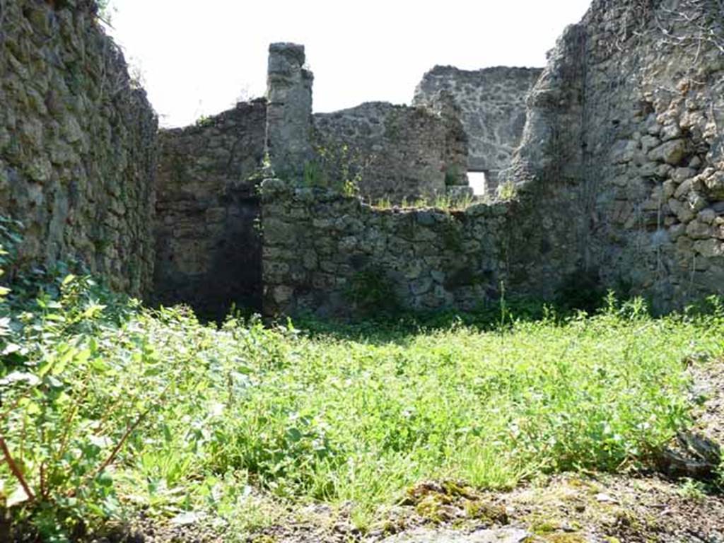 IV.16.35 Pompeii. May 2010. Rear room, kitchen I, on the east side. Looking west from VI.16.11. The doorway into the kitchen from the corridor is in the rear (west) wall on the left of the picture. Soglianos description was written as arriving into the kitchen from this corridor. Our picture was taken from the other side of the room.
According to NdS, corridor G turned at right-angle to the north, and then again at right-angle to the east, where it immediately opened into the kitchen, room I.
The hearth c leaned to the left end of the east wall, (right front of this photo).
It had roof tiles on its edge and an arched empty space below.
Perpendicular to the south wall were two parallel walls, which formed two small rooms, (area on the left of this photo).
Room d was the latrine.
Room e was a repository.
See Notizie degli Scavi di Antichit, 1908, (p.359-363)