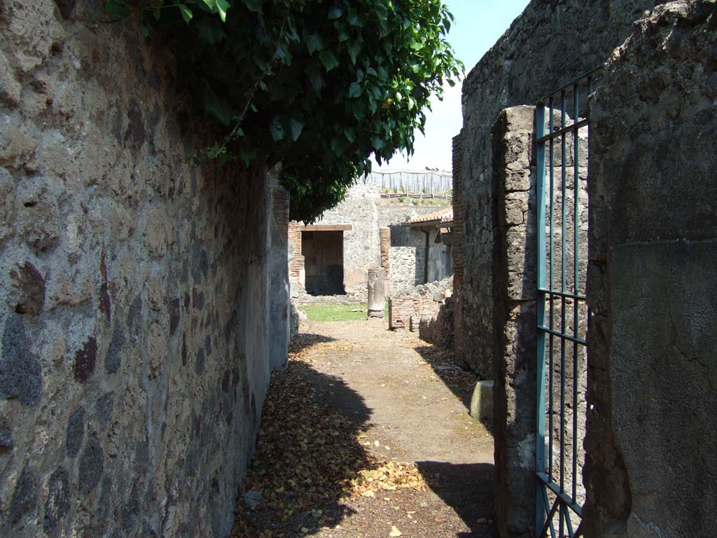 VI.16.36 Pompeii. May 2006. Looking east from entrance corridor A.
On the right of the entrance corridor A is the doorway leading to corridor (a) in shop B.
On the east side of this doorway, corridor A widens into room C and room D, ahead.
On the south side of these two rooms would be room E, behind the doorway to corridor (a), and at the far end of the photo on the right, the low walls of room F can be seen.
