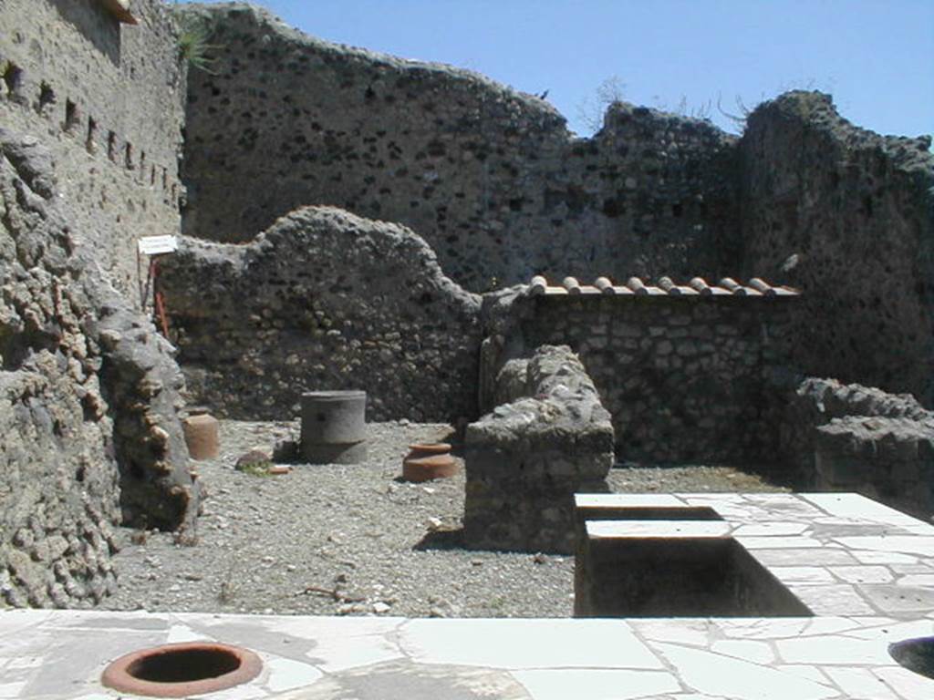 VI.16.40 Pompeii. May 2005. Room B, looking east across counter towards two rear rooms C and D and a corridor E to rear, leading to rooms F and G. According to NdS, room B was the bar-room, around which were smaller rooms. Adjacent to the north wall, near the entrance doorway, was the two-sided masonry sales counter or podium. At the other end  in the centre of the bar-room, it ended with a kitchen oven (a), also in masonry. The external vertical surface of the sales counter was painted in red. The horizontal surface was decorated with embedded triangular slabs of marble and other shapes. Leaning against the north wall were the usual three small masonry steps, painted in red, to display the goods and housewares. The room was rather rustic.

At the east end of the north wall of the bar-room, near the doorway to room C, was a doorway to the area below the stairs at VI.16.39. Rooms C and D were rooms for the use of the clients of the bar. When excavated, the entrance doorposts on the left showed the imprint left by the timber. At the north end of room G, behind room C, was the latrine (b).
