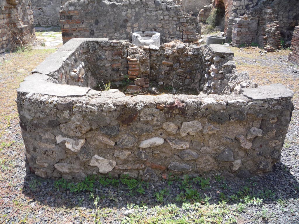 VII.1.36 Pompeii. October 2009. Looking south across large tub or basin in atrium. Photo courtesy of Jared Benton.
According to Scafati, from the entrance corridor one entered the atrium with several rooms on the sides, and where in the middle was a basin of masonry in which one could see a lead pipe and various tubes of terracotta to regulate the flow of water. Then one passed into the locality of the mills and oven, which was found shut with a bar of iron across it, and contained 81 loaves, well preserved and now to be seen in Naples Museum and Museum at Pompeii. 
See Scafati, (1900): Guide to Pompei illustrated, (p.62)
According to Breton, in the centre of the atrium was found a square masonry impluvium of an exceptional shape because its sides were not less than 0.80m height above the ground: the water was brought by a visible lead pipe. On the left was a large terracotta puteal mended with lead straps.
See Breton, Ernest. 1870. Pompeia, Guide de visite a Pompei, 3rd ed. Paris, Guerin. 
