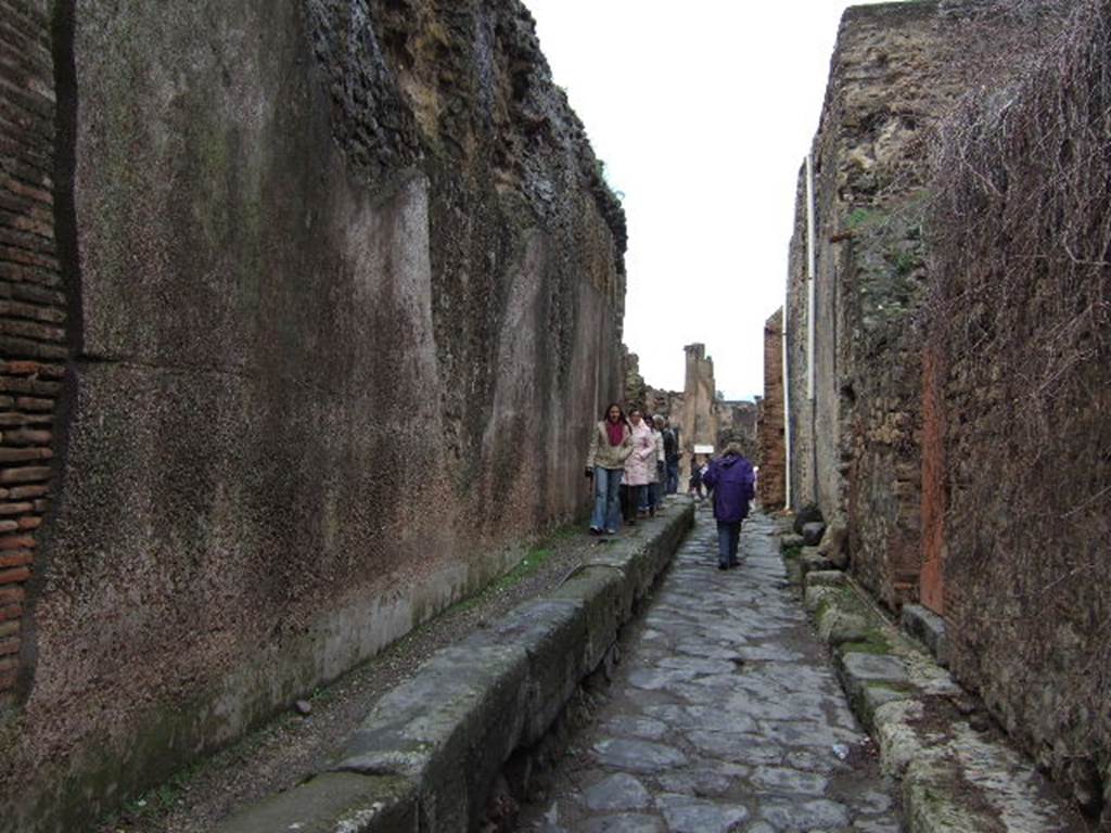 VII.6.17 Pompeii on the left. December 2006. Vicolo delle Terme looking north with VII.5 and Forum baths on the right. Between VII.6.16 and VII.6.17 are three large water storage reservoirs that feed the Forum Baths. These are behind the wall on the left. The tanks were 5m by 15m at the base and 9m high at the top of the curved roof. It is estimated the reservoirs held 430,000 litres of water. See Eschebach, L., 1993. Gebudeverzeichnis und Stadtplan der antiken Stadt Pompeji. Kln: Bhlau. (p. 41).