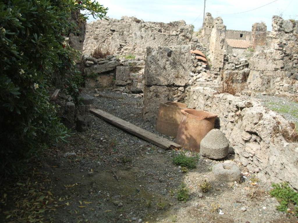 VII.6.21 Pompeii. May 2005. Remains of small millstone in shop area, and two terracotta pots.