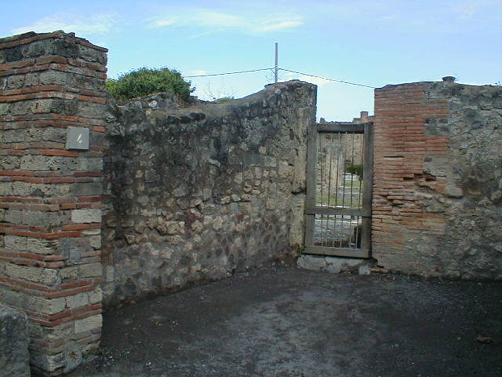 VII.7.4 Pompeii. September 2004. West wall, and doorway to atrium of VII.7.5 in north-west corner.  According to Eschebach, on the left would have been the steps to the upper floor, on the right a lararium niche.
See Eschebach, L., 1993. Gebäudeverzeichnis und Stadtplan der antiken Stadt Pompeji. Köln: Böhlau. (p.299). 
According to Boyce, in the east wall was an arched niche.
See Boyce G. K., 1937. Corpus of the Lararia of Pompeii. Rome: MAAR 14. (p.68, no.296) 
