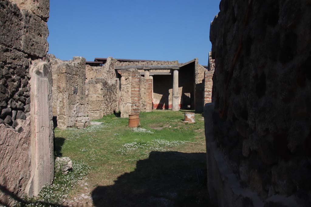 VII.7.10 Pompeii. September 2017. Looking north from entrance doorway towards rooms on north-west side of atrium.
Photo courtesy of Klaus Heese.
Pagano diceva –
“Dal vestibolo o protiro si passa all’atrio col suo impluvio nel mezzo per raccogliere le acque piovane, ed accosto al medesimo sta la bocca di un piccola cisterna. Lateralmente sono disposte quattro stanzette da dormire, cubicoli, con due ale; e da quella a sinistra si passa in un’apotheca che conteneva tre scansie di legno, di cui rimangono le impronte. Tra il secondo cubicolo e l’ala a dritta, trovasi collocato un masso rettangolare di pietra Vesuviana, ove appariscono tracce di osside di ferro. Era quello il posto ove tenevasi la cassa del peculio di quel proprietario, la quale era anche fermata al muro mediante una placca di ferro, che esiste tuttora in buona parte.
Di fronte all’ingresso era la sala di ricevimento, tablino, ed a dritta di esso, in quella sala preceduta da due gradini di marmo bianco, trovasi dipinta la lupa che nutrisce i gemelli.
A sinistra del medesimo tablino sta uno stretto pasaggio, fauces, che mette nell’interno dell’abitazione destinata per le donne. Il centro era abbelito da giardinetto di fiori, ed il muro di prospetto mostra un grandioso dipinto di animali, cioe un serpente avvolto ad un tronco, un elefante, un toro, un muletto, un caprio, un leone, una volpe, un orso. A sinistra era rappresentato un giardino con fontana fiancheggiata da Cariatidi, da un grosso pavone, e sormontata dal simulacro di Sileno sdraiato sull’otre.
Dalla porta a sinistra si entra nella stanza da pranzo, seguita dalla cucina, munita di cesso (ora restaurato con legno moderno).
Sul lato dritto dello stesso giardino era un recesso senza porta, ove apparisce il sito della scalinata di legno, che menava al piano superiore.
Finalmente in fondo era la porta postica o di uscita, sporgente in un vicoletto.”
See Pagano, N. (1881). Guida di Pompei, ed.9. (p.13-15). (see under photo below, for translation).

