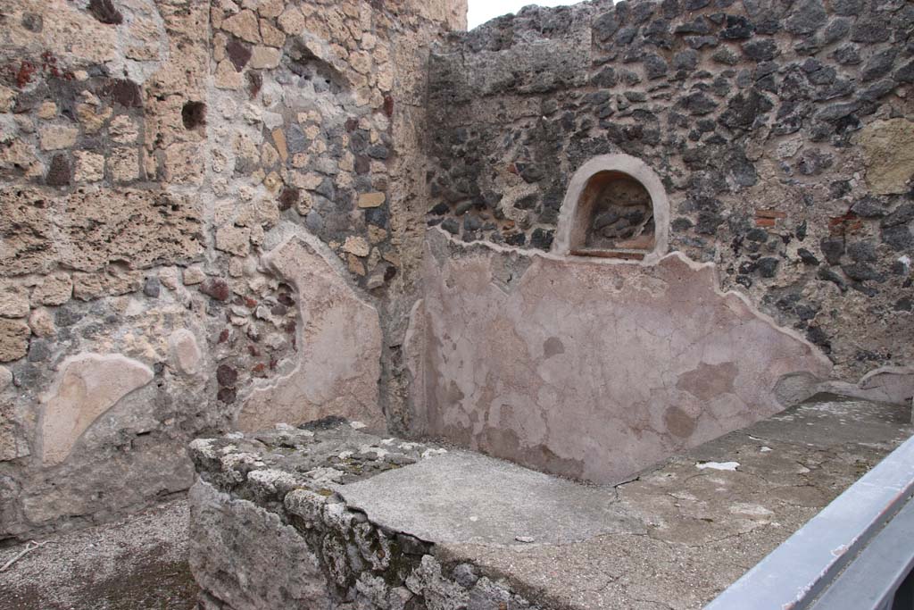 VII.7.11 Pompeii. October 2020. Looking north-east across two-sided sales counter in shop towards lararium niche. Photo courtesy of Klaus Heese.