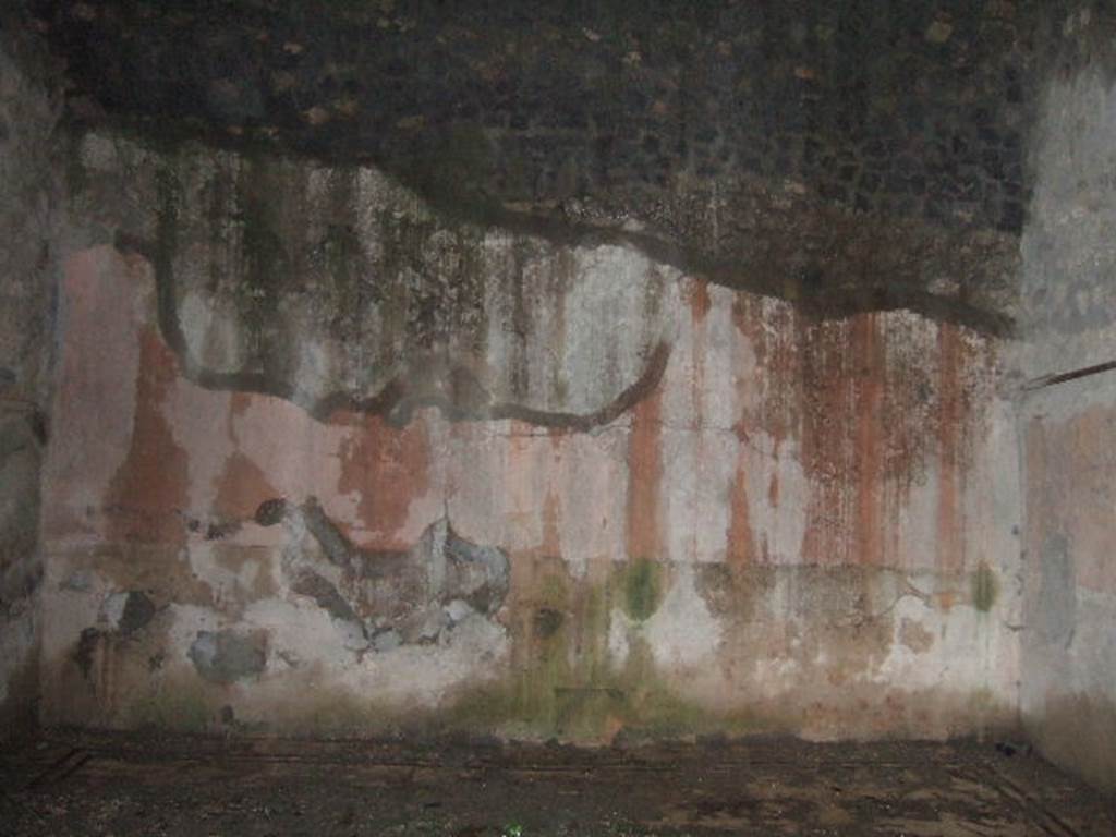 VII.10.3 Pompeii. December 2005. Room 14, east wall of exedra/oecus, at rear of peristyle garden. According to Fiorelli, two paintings were found in the exedra. One represented the head of Dionysus crowned with ivy leaves, with his head beside a Baccante appearing near his shoulder. The other was circular showing Perseus holding up the head of Medusa, to show the reflection in the water to Andromeda, who rests on his shoulder. On one side of the exedra are two other rooms, of which the second was used perhaps for a dormitory
See Pappalardo, U., 2001. La Descrizione di Pompei per Giuseppe Fiorelli (1875). Napoli: Massa Editore. (p.108)
According to Bragantini, the floor was black and white mosaic. In the centre was an emblema of opus sectile showing squares and triangles in coloured marbles. The walls were painted in the IVth style with a black zoccolo containing panels showing painted plants. The middle zone of the walls was red. On the south wall, in the centre of the black zoccolo was a yellow panel with painted plants. In the centre of the middle zone was a yellow panel with a painting, no longer recognisable.
See Bragantini, de Vos, Badoni, 1986. Pitture e Pavimenti di Pompei, Parte 3. Rome: ICCD. (p.177-8)
According to Richardson, found in the “triclinium” on the east side of the peristyle, were a painted bust of Bacchus and a maenad (Sommer negative 11918)
See Richardson, L., 2000. A Catalog of Identifiable Figure Painters of Ancient Pompeii, Herculaneum. Baltimore: John Hopkins. (p.127)
According to Helbig, found in the “triclinium” behind the peristyle was a painting of Perseus and Andromeda, (1198), and Bust of Dionysus, (385).
See Helbig, W., 1868. Wandgemälde der vom Vesuv verschütteten Städte Campaniens. Leipzig: Breitkopf und Härtel. (1198 and 385).
According to Amoroso, the exedra (our room 14) stood behind the viridarium and was decorated with a bacchic scene and with a pinax circolare in which were figured Perseus showing Andromeda the severed head of Medusa reflected in the water. 
Studi della Soprintendenza archeologica di Pompei, 22: l”Insula VII, 10 di Pompei, by Angelo Amoroso, (p.274) 
