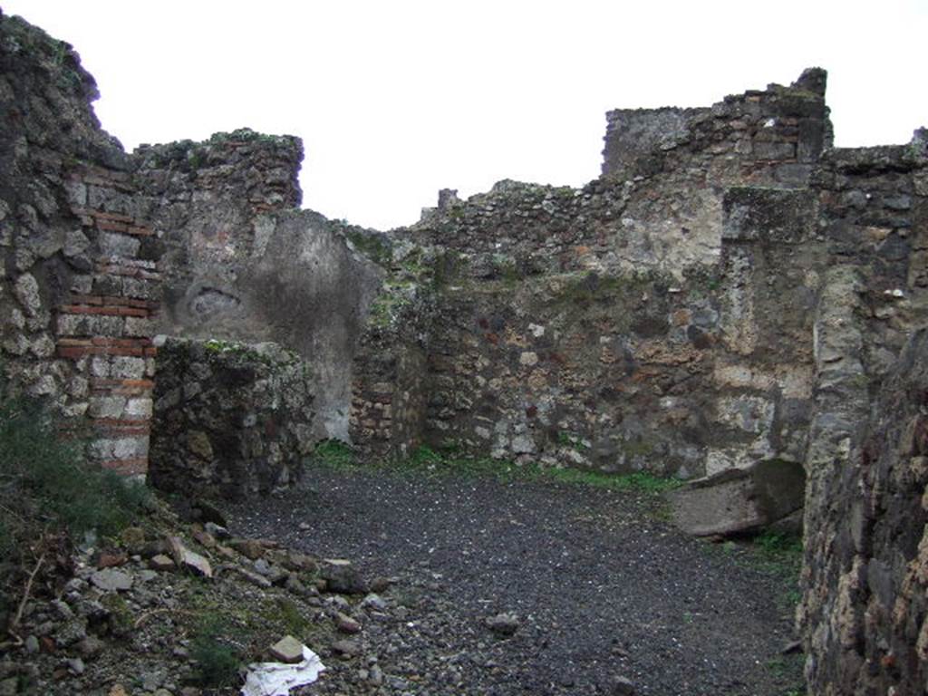 VII.13.12 Pompeii. December 2005. Looking west across kitchen, with remains of hearth (on left). Looking towards the yard, on the north side of the rear room of the shop.
