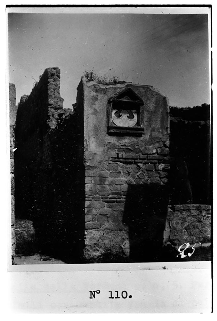 VII.16.7 Pompeii. W.1594. Marble pelta, in situ. This was bombed in 1943 and destroyed.
Photo by Tatiana Warscher. Photo © Deutsches Archäologisches Institut, Abteilung Rom, Arkiv. 
According to Fiorelli -
“Questa bottega tiene sul pilastro che la precede un’edicola di fabbrica, ed in essa una pelta marmorea, con rilievo di due maschere tragiche e due faci, gia servita a decorare l’intercolunnio del portico di qualche ricca abitazione, e poi posta qui come segno averrunco contro il fascino”. 
(translation: This shop had a masonry aedicula on the pilaster that preceded it, and in it was a marble pelta with the relief showing two tragic masks and two faces, formerly used to decorate the intercolumniation of the portico of some rich house, and then placed here as a sign against the evil-eye. 
Vedi/See Pappalardo, U., 2001. La Descrizione di Pompei per Giuseppe Fiorelli (1875). Napoli: Massa Editore. (p.161)
