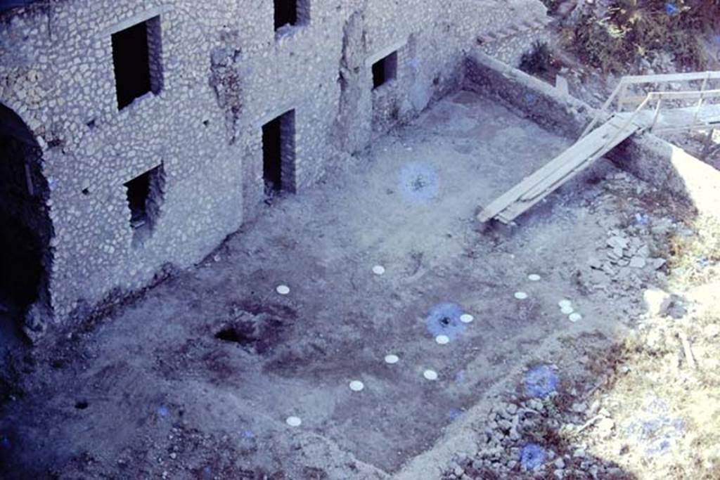 VII.16.17, Pompeii. 1974. Looking south-west from the courtyard garden, down onto lower garden.  According to Jashemski, the garden was badly damaged and piled with building debris in 1974, but in the south part they were able to find root cavites (the white markers) arranged informally in rows.  Photo by Stanley A. Jashemski.
Source: The Wilhelmina and Stanley A. Jashemski archive in the University of Maryland Library, Special Collections (See collection page) and made available under the Creative Commons Attribution-Non Commercial License v.4. See Licence and use details. J74f0706
