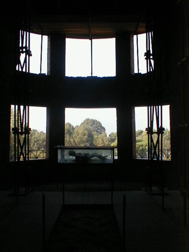 VII.16.17-22 Pompeii. September 2004. Curved apse with six windows.
A plaster cast made of a body is on display in the case.

