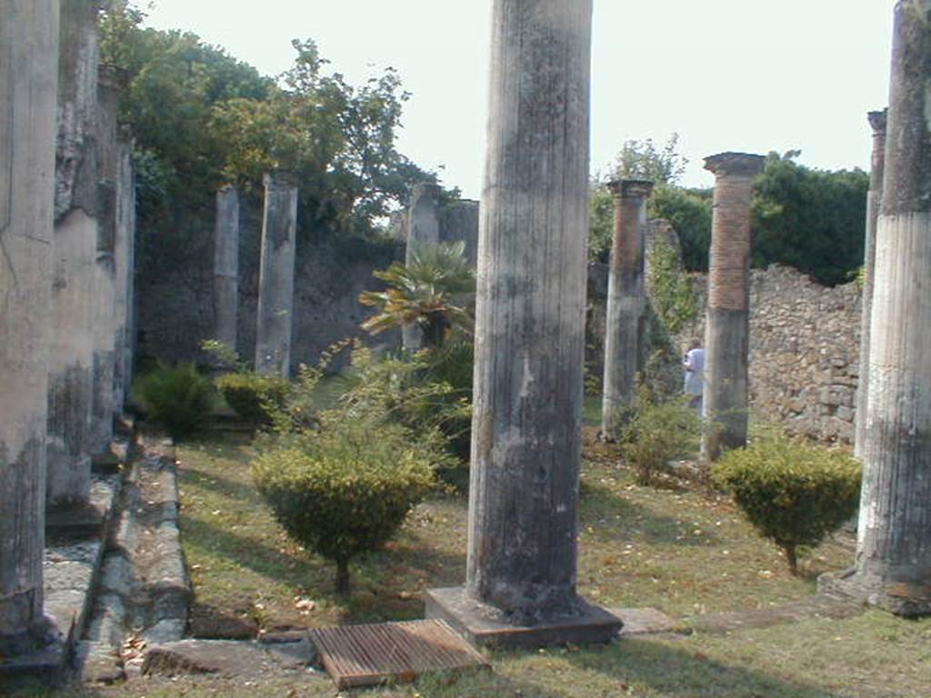 VIII.3.8 Pompeii. September 2004. Peristyle, looking south towards the large exedra.
According to Breton - 
“two columns were placed on pedestals decorating the entrance to the oecus, where the mosaic paving has only preserved a few remains of the beautiful greek white, black, red and yellow that surrounded it.”
See Breton, Ernest. 1870. Pompeia, Guide de visite a Pompei, 3rd ed. Paris, Guerin, (p.453).

