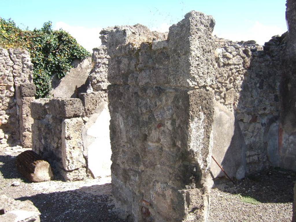 VIII.6.11 Pompeii. September 2005. Looking south-east towards rooms on south side of bakery. 
Doorway to room “c”, on the right. According to Mau, room “c” had simple decoration on a white background and a floor of opus signinum; a shelf was attached to the right wall and the rear wall. (“c” ha semplicissime pitture a fondo bianco e un pavimento di opus Signinum; al muro “d” e di fondo era attaccata una scansia.) 
Entrance corridor.
Doorway to room “b”, on the left. According to Mau, “b” was the panificium: against the east wall was a masonry foot of a large table: the other foot must have been made of wood.
In the rough-covered plastered walls one could see the holes for the supports of three shelves. The floor was made of opus signinum varied with white stones arranged irregularly
(“b” è il panificium; addosso al muro E sta un piede murato della grande tavola : l'altro piede dev'essere stato di legno. Nelle pareti, rivestite d'intonaco grezzo, si vedono i buchi dei mutuli per tre scansie. Il pavimento è formato di opus Sìgninum variato da pietruzze bianche disposte irregolarmente.)  See BdI, 1884, Page 138-9
