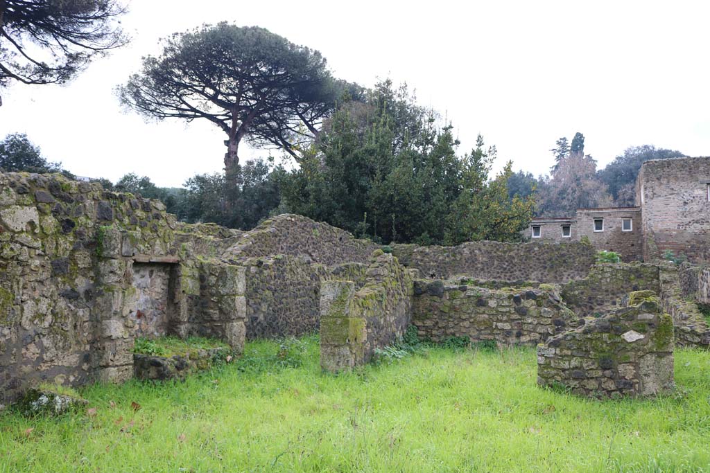 VIII.7.8 Pompeii. December 2018. 
Looking south-west from entrance doorway, towards south wall with kitchen/bench and corridor to rear, on left. Photo courtesy of Aude Durand.
According to Mau –
“In the north-west corner of the large room, there was the remains of a brick column, in the south-west corner there was a mass of masonry in the form of a bench or a low table, and at the foot of it towards the east were two round basins (diam. c.0.42), however of a not entirely regular shape, one of which widens in the lower part.”
See Mau in BdI, 1875, (p. 165 – Terza casa).


