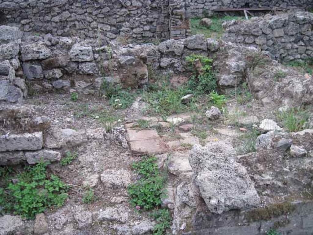 VIII.7.12 Pompeii. September 2010. 
Remains of kitchen (?) area, the third room south of corridor, with feature of raised platform with tiled top. Photo courtesy of Drew Baker.
According to Mau, this is one of the two small rooms, but no mention of a kitchen area.
See Bullettino dell’Instituto di Corrispondenza Archeologica (DAIR), 1875 (p.169).
According to PARP:PS – there was a hearth/cooking facilities (no.6 on their plan) against the north wall in the rear area.

