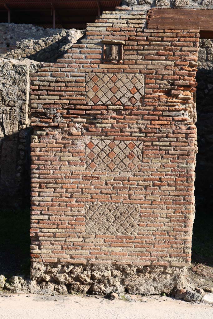 IX.1.13 Pompeii, on left, and IX.1.14, on right. December 2018.
Looking east to pilaster separating two entrances, with a tufa phallus set into a plaque.
Photo courtesy of Aude Durand.

