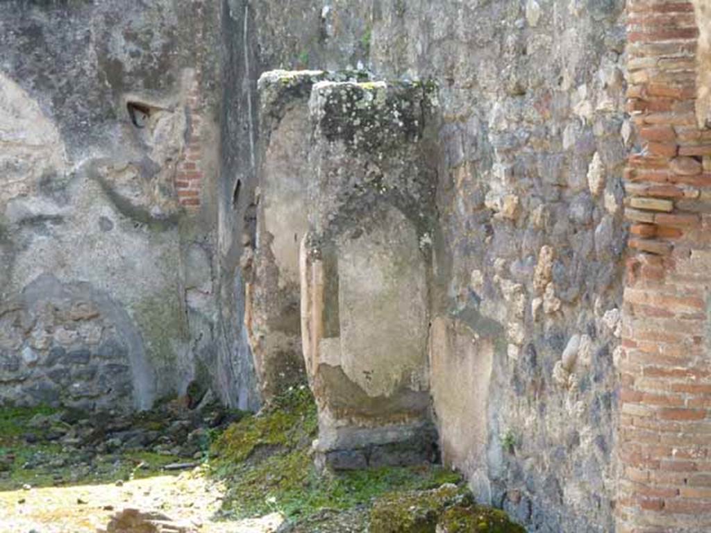 IX.2.27 Pompeii. May 2010. Remains of shrine on west wall.
According to Boyce, the two enclosing walls formed a rectangular niche above a low podium, but none of the floor was preserved. The inside walls are painted blue with red borders. On the ground in front of the shrine stood a square masonry altar.
See Boyce G. K., 1937. Corpus of the Lararia of Pompeii. Rome: MAAR 14.  (p. 82)
