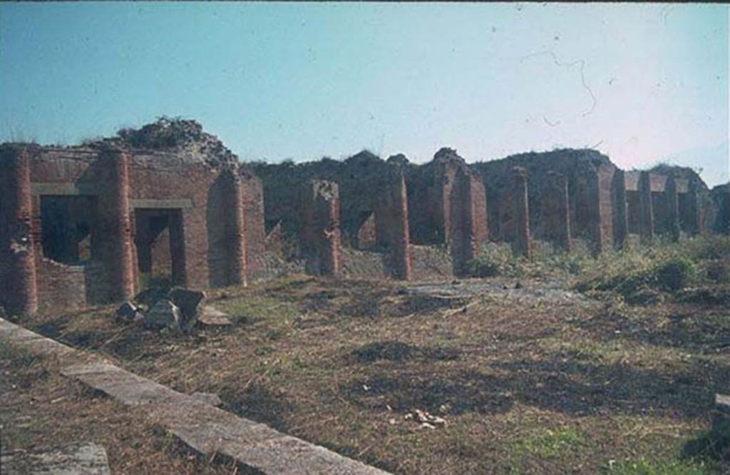 IX.4.18 Pompeii. East side of baths, looking south-east. 
Photographed 1970-79 by Günther Einhorn, picture courtesy of his son Ralf Einhorn.
The doorway on the left would have led to the apodyterium (changing room) “i”.
In the centre would have been the three windows of the frigidarium (cold) “p”.
On the right are the three large windows of the tepidarium (warm) “q”.
The caldarium (hot room) “s” would be the room with three square windows, on the right. 
