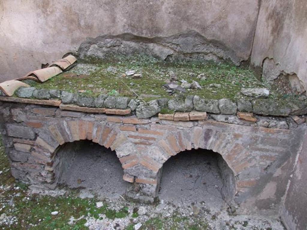 IX.5.6 Pompeii. December 2007. Room p, hearth/bench in kitchen, looking east.  
According to Giacobello, traces of a not very legible fresco found on the north wall of the kitchen near the bench were interpreted as a lararium. 
This was at the time of excavation.  See Mau in BdI 1879, p.116.
See Giacobello, F., 2008. Larari Pompeiani: Iconografia e culto dei Lari in ambito domestico. Milano: LED Edizioni, (p.285).

