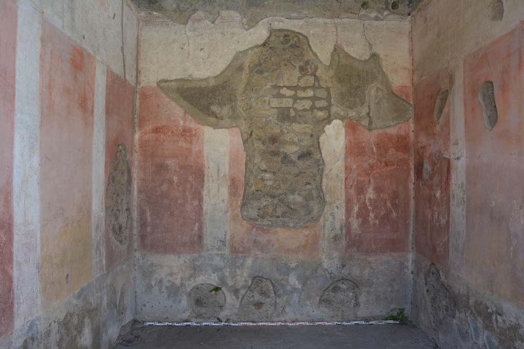 IX.5.11 Pompeii. May 2017. Room e, looking towards west wall.  
Foto Christian Beck, ERC Grant 681269 DCOR.
According to Bragantini (1979) 
West wall with hole, the zoccolo was painted black with panels with carpet borders of two parallel lines separated by narrow compartments.
The middle zone had a central yellow panel and red side panels.
The upper zone was white with a stucco cornice. 

