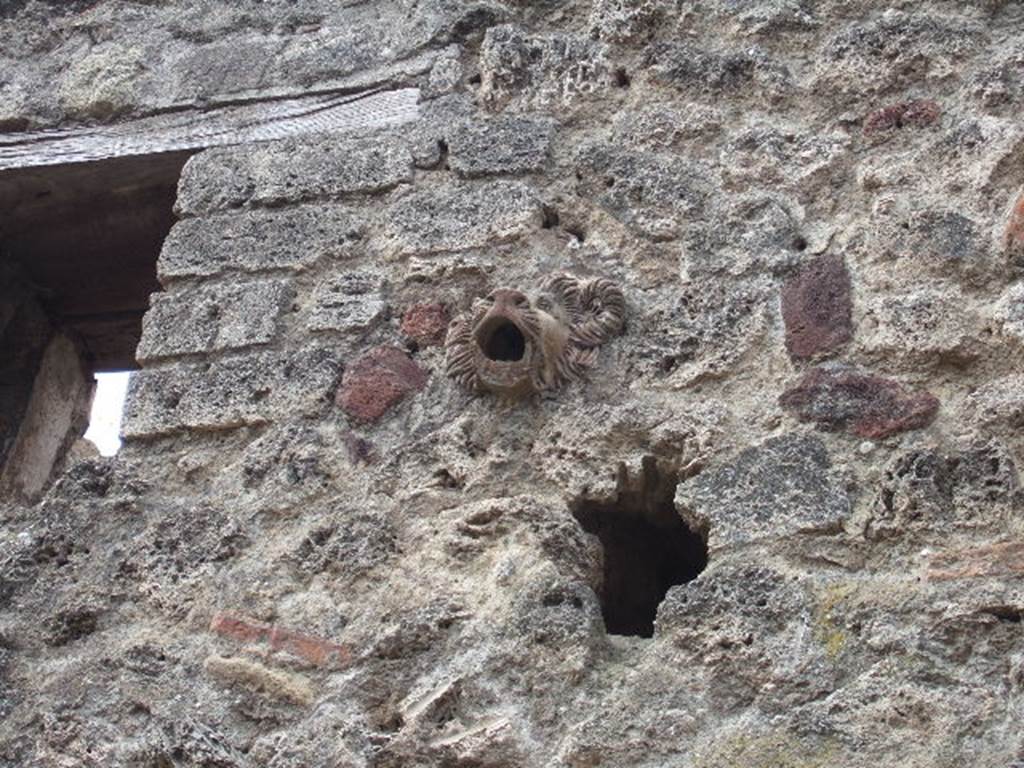 IX.5.13 Pompeii. May 2006. Faces in stonework high up on front wall.