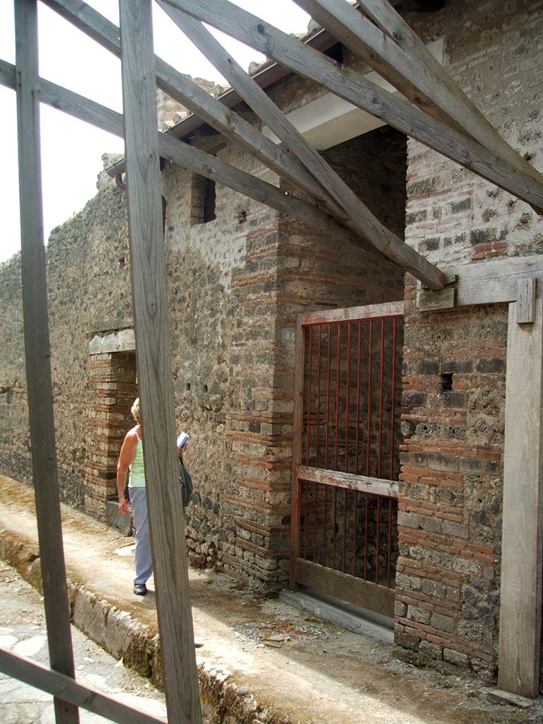 IX.5.15 Pompeii, on left, and IX.5.14, centre right. May 2005. Entrance doorways.
According to Mau, when excavated bronze studs were found that had decorated the door at number 14, together with an iron key. 
See Bullettino dell’Instituto di Corrispondenza Archeologica (DAIR), 1879, (p.207).
