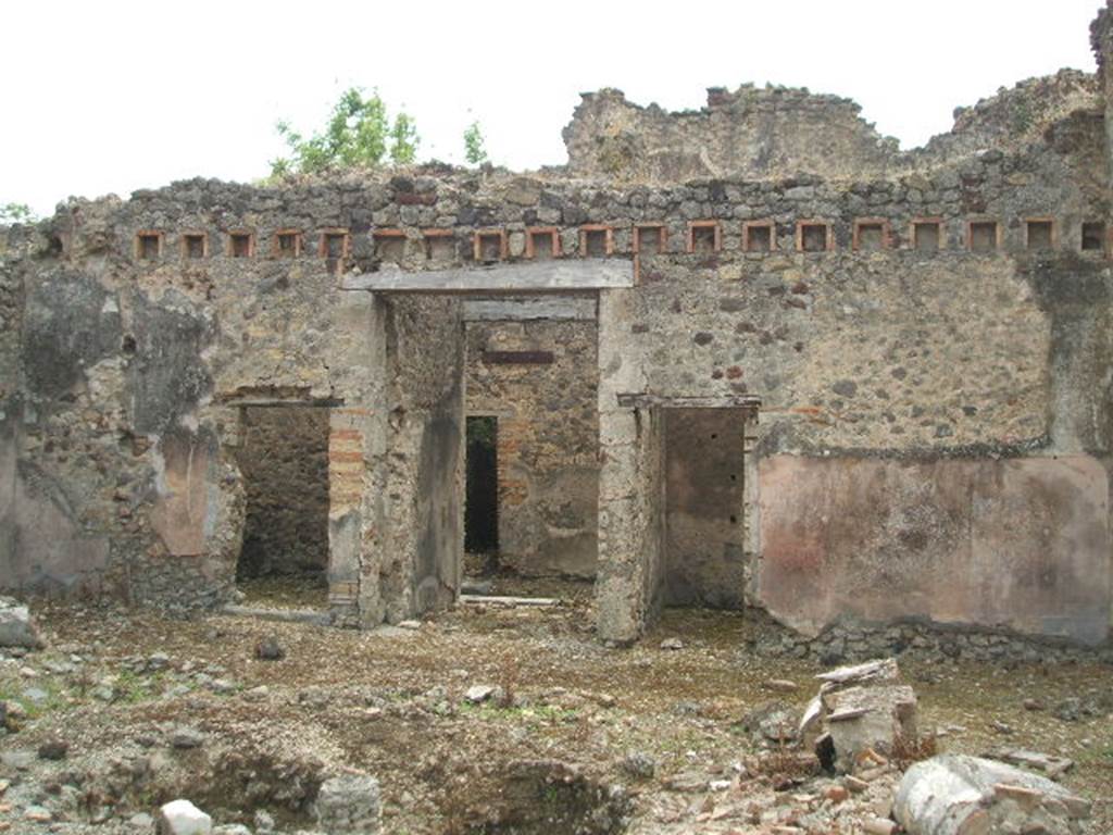 IX.5.18 Pompeii. May 2005. Looking south across atrium, room b, towards the entrance doorway, in centre. The doorway on the left leads into room h, which according to Zevi measured approximately 3.50m x 3.70m. It was the kitchen area with a latrine and masonry hearth. The walls were roughly plastered but on the left  (east) wall was a simple decoration consisting of a yellow zoccolo, and red upper face to the walls.
See Zevi, F., 1964.  La Casa Reg IX.5.18-21 a Pompei e le sue pitture: Studi Miscellanei 5.  Roma: Bretschneider. (p.9 and note 22)
