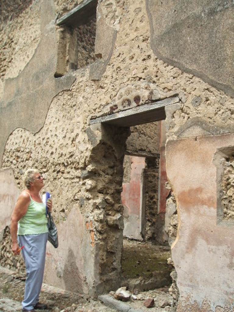 IX.5.19 Pompeii. May 2005. Entrance doorway, and south exterior wall, with window in upper floor. According to Della Corte, a graffito found on the east (right) side of the doorway, verified to him the family owning IX.5.1/2 as being the family Stronnia. It read - Stronni     [CIL IV 5124]
See Della Corte, M., 1965.  Case ed Abitanti di Pompei. Napoli: Fausto Fiorentino. (p.130).
Della Corte thought that the upper floor rooms above IX.5.18, leading up from the staircase, lead to a lupanar.  More than 50 inscriptions were found [CIL IV 5105-5158] written on the external dado to the side of entrance IX.5.19, which speak of many men and women prostitutes.  
He said, amongst the many names of the women written on the wall, the first was mentioned 8 times, the second 3 times, and the last two, also included their price, II and VIII asses respectively - Successa, Nebris, Phoebe, Glycera mordax, Optata, Spes.   
According to Epigraphik-Datenbank Clauss/Slaby (See www.manfredclauss.de), these are -
Optata
verna  a(ssibus) II       [CIL IV 5105]
[S]uccess[a]                 [CIL IV 5117]
Nebris Felixs(!) vale   [CIL IV 5118]
Vici
Glycera mordaxs(!)    [CIL IV 5120 and 5121]
Phoebe (v)eni              [CIL IV 5125]
Succesa                        [CIL IV 5130]
Succes(sa)
Successa                      [CIL IV 5131]
Successa                      [CIL IV 5137]
Nebri(s)                          [CIL IV 5145]
Suces(s)a N() C()         [CIL IV 5150]
Suc(ces)sa                    [CIL IV 5153]
Spes
a(ssibus) II                    [CIL IV 8511]     (Note this is quoted as II assibus and not VIII, as Della Corte wrote)
 Another local, named Somene, [CIL IV 5122 and 5123] was also mentioned here, and also in the house at IX.5.9 – Somene nequ(am)!    [CIL IV 8322k]  See Della Corte, M., 1965.  Case ed Abitanti di Pompei. Napoli: Fausto Fiorentino. (p.162-3)
According to Epigraphik-Datenbank Clauss/Slaby (See www.manfredclauss.de), they read - Somene    [CIL IV 5122]
Somene dupu(n)diu(m)  (denariis) L loc(at)    [CIL IV 5123]
Della Corte thought Mau (and Epigraphik-Datenbank) had read this wrongly. (Note 1 on p.163).  He thought it said -
Somene depun(n)dium a(ssibus) L loc(at)    [CIL IV 5123]
