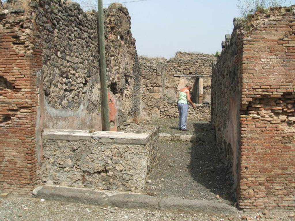 IX.6.b Pompeii. May 2005. Looking north across bar entrance. The podium of the bar/bench was decorated with fragments of marble.  According to Varone, found on the wall between entrances IX.6.a and b (on the left) were CIL IV 5203, 5204 and 5206.  He said that these vernae (slaves born into the household, appeared to be offering themselves for prices between 5 to 8 asses.  See Varone, A., 2002. Erotica Pompeiana: Love Inscriptions on the Walls of Pompeii, Rome: Lerma di Bretschneider. (p.144)
According to Epigraphik-Datenbank Clauss/Slaby (See www.manfredclauss.de), they read as -
Rogas 
verna 
(a)eris  VIII    [ CIL IV 5203]
Al[3]re 
erna  aeris  V    [CIL IV 5204]
Verna  aeris  L   [CIL IV 5206]
According to Della Corte, this bar had a sales-podium and two rooms to welcome clients. Also found on the pilaster to the left of the entrance, was the electoral recommendation - Marcus  cum  Une ..o. (rogat)    [CIL IV 3728].  See Della Corte, M., 1965.  Case ed Abitanti di Pompei. Napoli: Fausto Fiorentino. (p.193)
According to Epigraphik-Datenbank Clauss/Slaby (See www.manfredclauss.de), this read as 
P(ublium)  Paquium  Procul(um) 
d(uumvirum)  v(iis)  a(edibus)  s(acris)  p(ublicis)  p(rocurandis)  o(ro)  v(os)  f(aciatis)  Marcus 
cum  une[3]O[3]       [CIL IV 3728]
 According to Sogliano, found on the red plastered sales-podium was a very clumsily painted hunt scene, which had nearly all vanished when found. Here could be seen a horse fleeing to the left being bitten on the side by a tiger. Underneath this, was an ox, nearly disappeared (faded). More to the left, an unrecognisable animal of small proportions. 
Approximately in the upper middle, there was a deteriorating masculine figure, that struck a fleeing tiger with a lance to the right, and underneath another wild beast crouching on its back legs. 
More to the right one could have seen a deer fleeing in this direction, jumping on its back was a dog that was biting it. Underneath this even more, a tiger fleeing to the left, and in front of the deer an animal of small proportions. Not.di Scavi d. Ant, 1879, p.21 sg. See Sogliano, A., 1879. Le pitture murali campane scoverte negli anni 1867-79. Napoli: (p.138-9)
According to Mau, on the upper part of the external side of the dividing pilaster (on the right, between his no.12 and 13, and ours numbered IX.6.b and IX.6.c) a rectangle (0.92 high x 1,12 long) was found. It was divided into squares by black lines (six horizontal lines, and eight vertical) that were alternatively either white or coloured blue/purple, green and yellow. Seen under the lowest black line of the rectangle was painted the inscription (also published in Notizie degli Scavi, 1879, p.22) which read 
IVDICIS .  AVGVSTI . P . P. ET . POPPAEAE . AVG . FELICITER .
Under the pilaster, a masonry seat was made covered with red stucco. It was not clear whether the seat or the inscription belonged to one or the other of the adjacent shops.
See also Mau in BdI 1881, (p.30-2)
