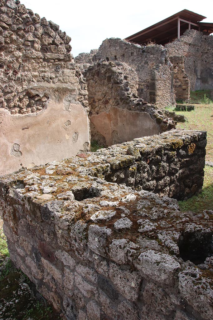 IX.7.22 Pompeii. October 2024.
Looking south-east across counter towards doorway into room on east side of bar-room, in centre.
On the right is a doorway into the atrium of IX.7.21. Photo courtesy of Klaus Heese.
