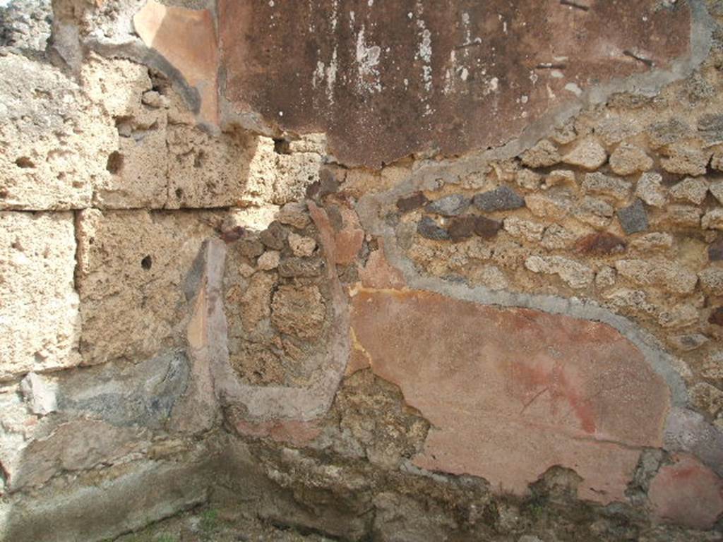 IX.7.22 Pompeii. May 2005. Remains of painted plaster in north-east corner of the room on east side of caupona. According to Mau, this room was the only one that had well conserved plaster. It was painted simply and clumsily in the last IV style, and on a yellow background.
In the middle of each of the divisions on the walls, there were similar square paintings representing a bird pecking at fruit, on a yellow background. See Mau in BdI, 1882, (p.194)
According to PPP, the north wall had a red lower area. The east wall had the lower portion of the walls painted red, in the middle area were narrow red central divisions with yellow panels, the upper area was painted red. The south wall had the lower portion painted red, the middle section painted yellow with panels. See Bragantini, de Vos, Badoni, 1986. Pitture e Pavimenti di Pompei, Parte 3. Rome: ICCD. (p.507)

