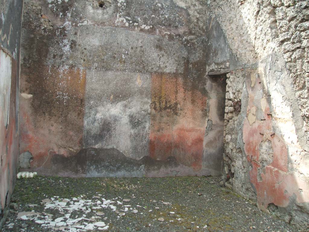 IX.7.25 Pompeii. May 2005. Looking south in tablinum “o”, with doorway in west wall to a small room or cupboard, room “n”.
According to Mau, when this house was being used as a hospitium, both the tablinum and ala were probably used as triclinia.
However, he conceded that in this tablinum, the couches would have made access to the small room on the right very difficult.
The rear wall of the tablinum was painted with a white background in the middle, with red on either side.
A painted flying cupid could be seen on the white background, with a thyrsus in his left-hand, a cantharus in his right, and a red cloak on his back.
See Mau in Bullettino dell’Instituto di Corrispondenza Archeologica (DAIR), 1882, (p.177 & 179)
