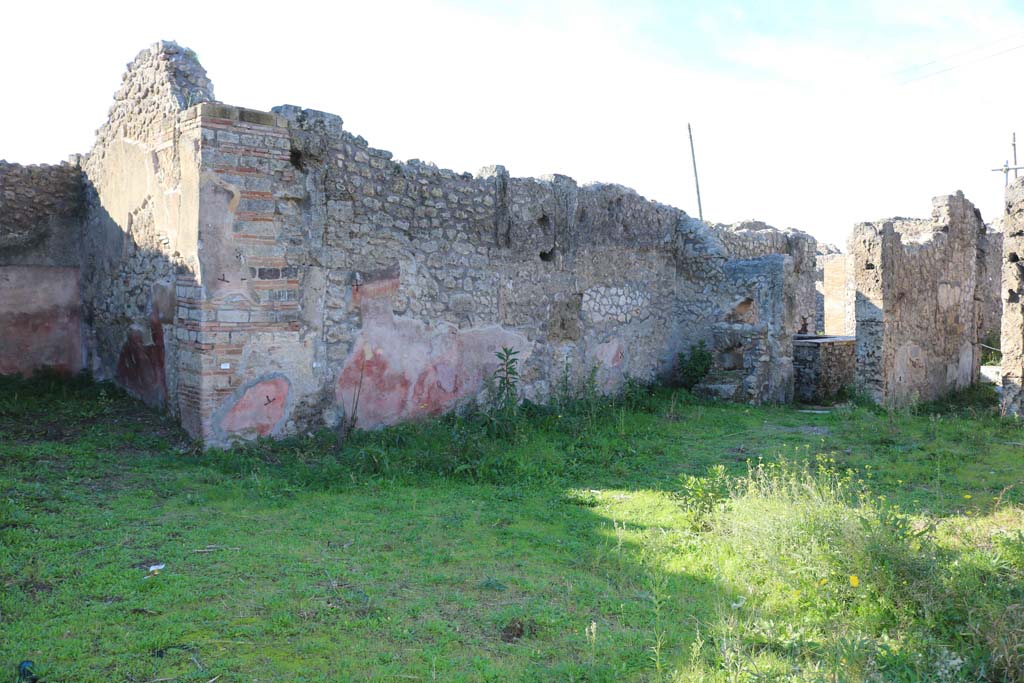 IX.7.25 Pompeii. December 2018. Looking towards north-west corner of atrium.
On the left is the ala/triclinium, on the right are the doorways to IX.7.24, and to the roadway. Photo courtesy of Aude Durand.
According to BdI –
Found in the atrium in a corner (19 Oct. 1880) the remains of a bronze or bronze-covered chest, i.e. plates with figurines, animals and bas-relief decorations, a lock plate and 2 handles; also « a crescent-shaped amulet (in bone) with a hole in the middle, ending at the two ends in the head of a phallus, length of the cord m. 0.04 ».
See Bullettino dell’Instituto di Corrispondenza Archeologica (DAIR), 1882, p. 178.

