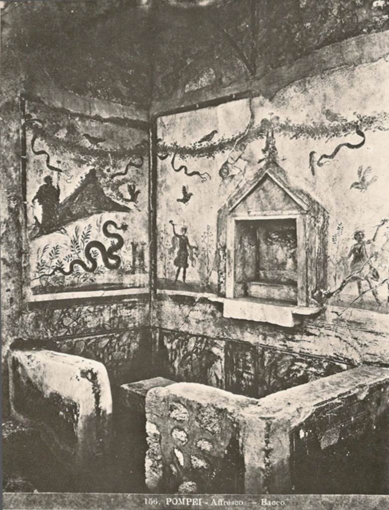 IX.8.6 Pompeii. Old photo no. 156, possibly just after excavation circa 1879-1881?  
Room 23. Servants’ quarters on west side of house. 
Household shrine or lararium with Bacchus painting still in situ.
According to Boyce –
In the south wall within the precinct is a rectangular niche (h.0.56, w.0.51, d.0.26, h. above floor 1.25), adorned with an aedicula facade (h.1, w.0.64), of grey marble, consisting of a plain rectangular slab on each side of the niche, a pediment above and a heavy block (0.12 thick) projecting on the level of the floor. Within the niche a low step is built against the back wall and in front of it a circular depression for offerings is cut in the block that forms the floor. In the pediment is painted an owl. On the wall on each side of the niche is the painted figure of a Lar with rhyton and situla, standing between two trees.
On the adjoining east wall is the panel with the famous painting of Bacchus beside Vesuvius…….. (Now in Naples Museum).
See Boyce G. K., 1937. Corpus of the Lararia of Pompeii. Rome: MAAR 14. (p.89-90, no.448).

