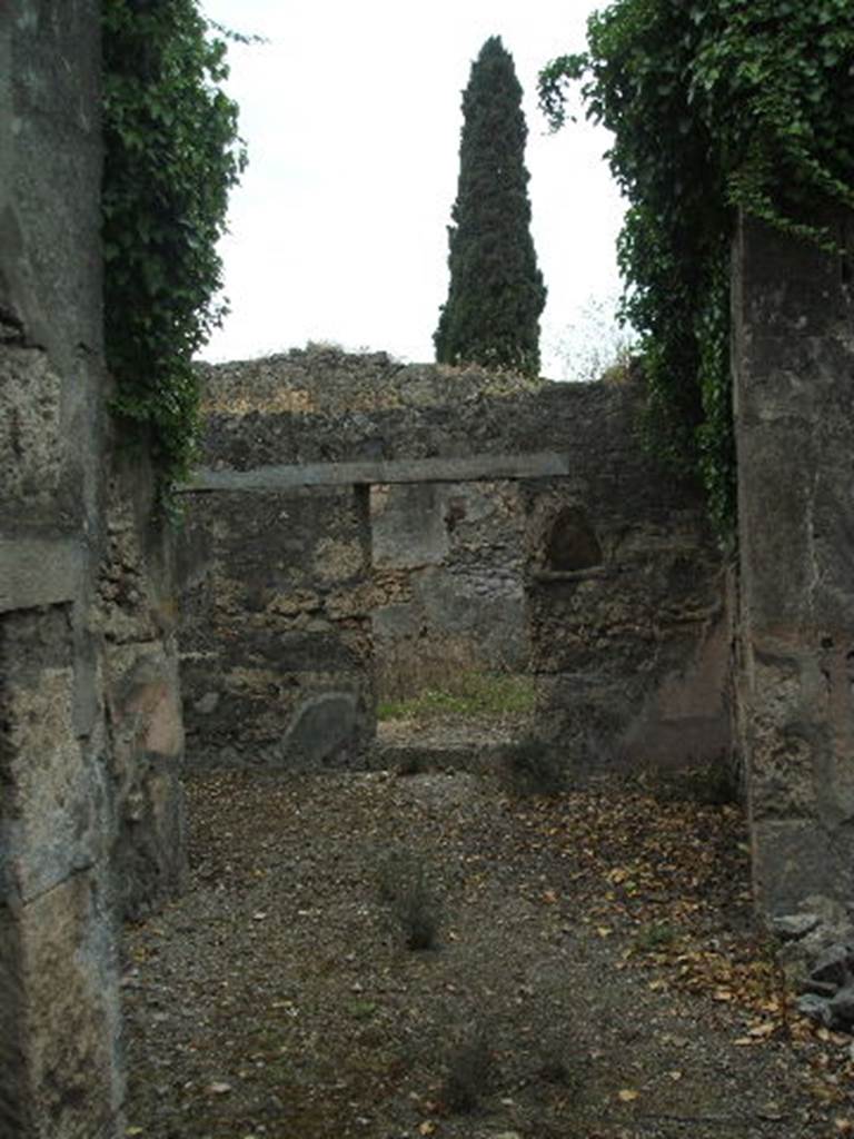 IX.9.11 Pompeii. May 2005. Looking west across atrium towards garden area, from entrance doorway. According to NdS, this small house or perhaps a hotel, was formed by a displuviate entrance hallway, four bedrooms, a dining room and a garden adjacent to it.
The atrium was entered down from the roadway by two small steps, now destroyed. It had a beaten floor with the walls covered in rough white plaster and a high zoccolo (dado) of crushed brick on the walls. In the north-east corner of the atrium was the latrine. Buried in the atrium wall, to the right of the doorway to the garden, at the height of a man, was a niche with a pointed arch, covered in white plaster and painted with the usual foliage and red flowers.
See Notizie degli Scavi, 1891, p.261.
