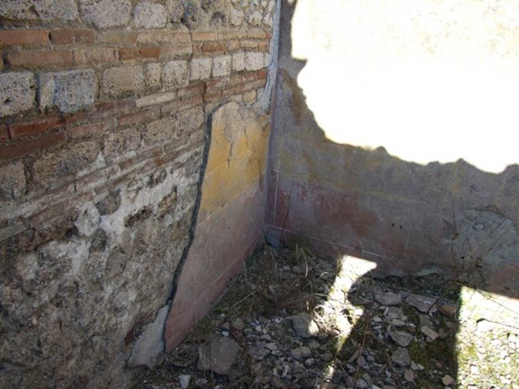 IX.9.a Pompeii. March 2009. North-east corner of cubiculum i.  This bedroom was described as having flooring of crushed brick (mattone pesto) and with pieces of coloured marble of various forms and sizes added to it. The walls were plastered, with a yellow background in the middle part, with a white frieze and red plinth or dado. In the middle of the yellow panels were rather crudely painted doves. See Notizie degli Scavi, 1888, p.515.
