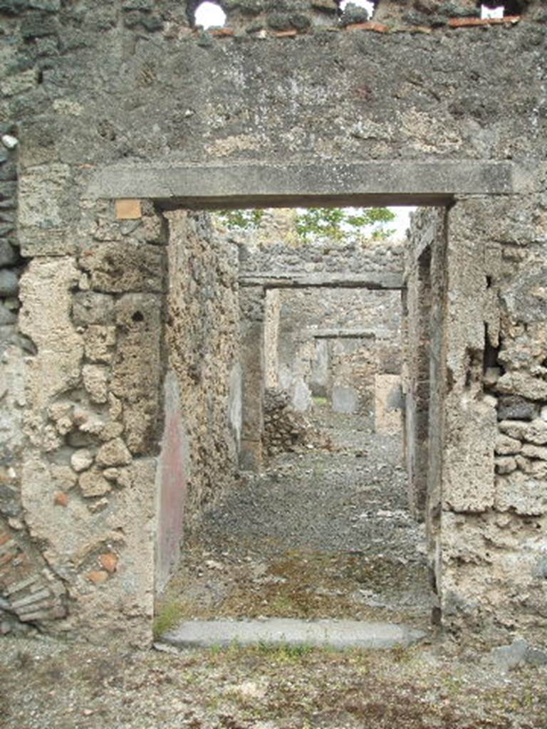 IX.9.e Pompeii. May 2005. Entrance doorway, looking east. According to NdS, the entrance doorway had a lava threshold. The doorway led into a long passageway with a beaten floor, the walls were covered with rustic white plaster. The lower section of the walls was covered by a high red zoccolo which was painted with yellow bands to separate it into panels.
See Notizie degli Scavi, 1891, p.255.
