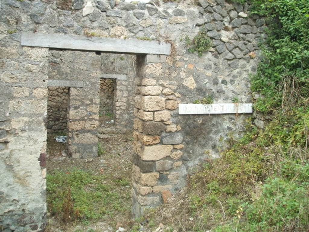 IX.9.g Pompeii. May 2005. Entrance doorway, looking east. According to NdS, this was the doorway to a modest house but had a painting advertising that this was the house of a painter of electoral programmata. The doorway led directly into the small atrium which had an attic above, as in the previous house (IX.9.f). The upstairs room had a balcony which jutted out into the roadway, but this had completely fallen when found.
See Notizie degli Scavi, 1891, p.264.
According to NdS, a graffito was found written in charcoal, on the inner surface of the right doorjamb. The doorjamb was faced with yellow painted plaster imitating coloured marble. The graffito showed  -
 XV| K AVG
XXX XXXV
LXX XV K AVG XL
LXX LX
LXX LX
LXX LX
L.. LX F
LXXX XIIII K aVG LX
LXXXX LX
.. xL xxxC  xLx
According to Sogliano, a drawing found on the right doorjamb showed a male figure in black outline (0.16 high). This was drawn almost from behind his shoulders, stretching his right hand forward, as if in the act of signing something on the wall, and was perceived certainly to be Aemilius Celer, shown in the act of painting slogans on the house-walls of Pompeii. Underneath in black letters, nearly vanished, was the wording - aemiliVS CELER.
See Notizie degli Scavi, 1888, p.520 (recorded as being from IX.7, near the seventh doorway in the side street)
