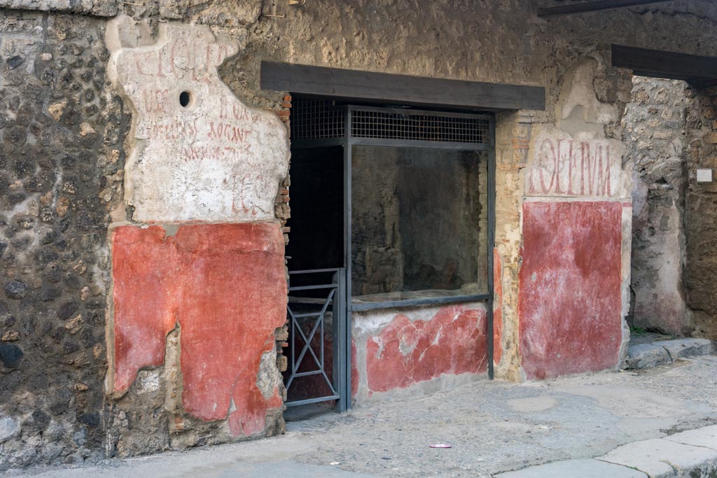 IX.11.2 Pompeii, in centre. October 2023. 
Entrance doorway with painted graffiti on both sides, with IX.11.3, on right. Photo courtesy of Johannes Eber.
