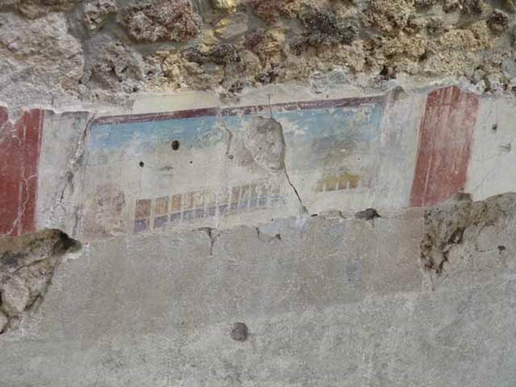 IX.12.5/4 Pompeii. May 2010. Detail of painted upper east wall in room being excavated, on west side of bakery at IX.12.6. 
According to Spinazzola, this painting showing a house with two-storey porticoes and windows, was the decoration of a zoccolo in a room on the upper floor.
See Spinazzola, V. Pompei, alla luce degli Scavi Nuovi di Via dell’Abbondanza (Anni 1910-1923), Vol.2, p.719, fig.690.
