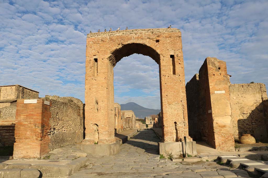 Via di Mercurio at the south end between VI.8, on left, and VI.10, on right. December 2018. 
Looking north through the Arch of Caligula into Via di Mercurio, from crossroads of Via delle Terme, on left, and Via della Fortuna, on right. 
Photo courtesy of Aude Durand.
