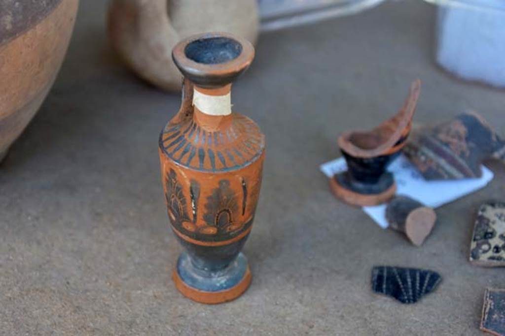 Santuario extraurbano del Fondo Iozzino. 2014 excavations. Perfume pot imported from Greece. A lekythos of attic production. A fragment of a black ceramic jug. To the right - fragments of a black ceramic jug.

Vaso di profumo importati dalla Grecia. Una lekythos di produzione attica. A destra frammenti di una brocca in ceramica nera.

Photograph © Parco Archeologico di Pompei.

Una brocca decorata con manico singolo e frammenti di una brocca in ceramica nera.

Photograph © Parco Archeologico di Pompei.
