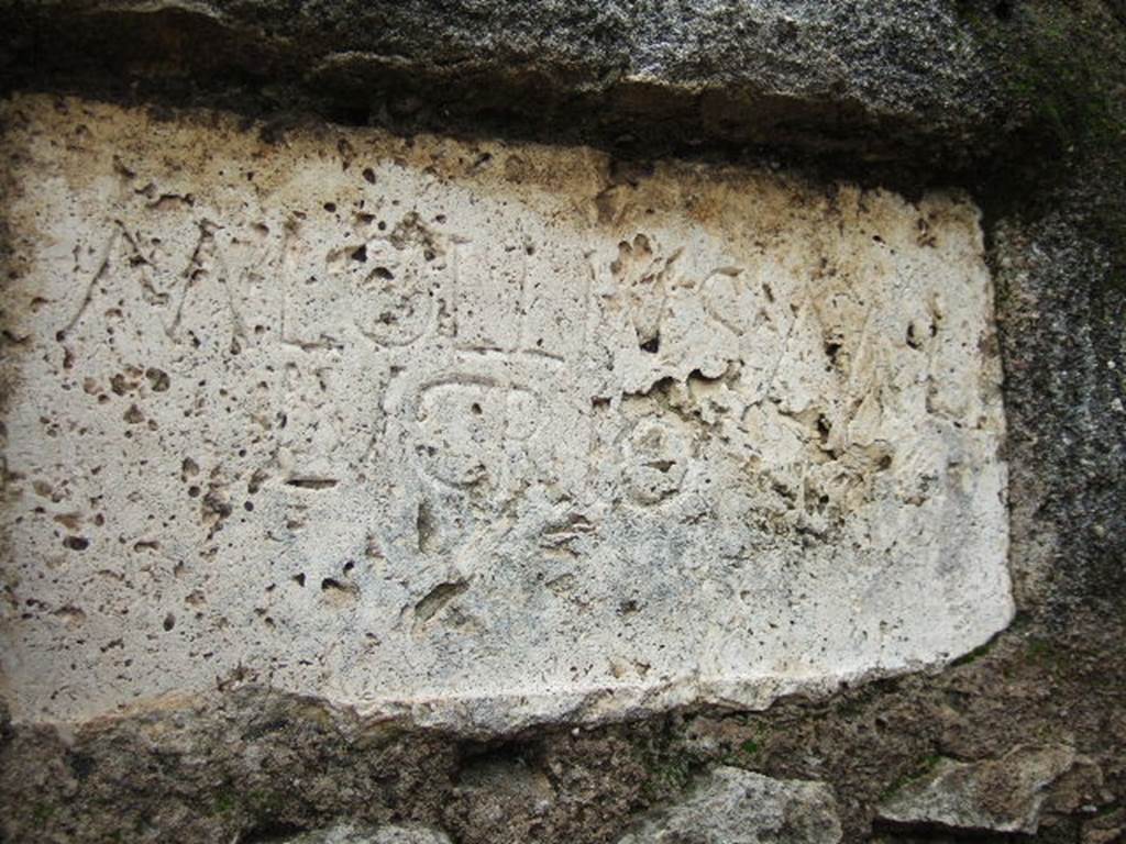 FPNI Pompeii. December 2005. Plaque on east end of south side with inscription:
According to D’Ambrosio and De Caro, this was possibly of non-local travertine and read

M. LOLLIVS M L 
LVCRIO.

They expand this to

M(arcus) Lollius M(arci) l(ibertus)
Lucrio

See D’Ambrosio A. and De Caro S., 1988. Römische Gräberstraßen. München: C.H.Beck. p. 214.