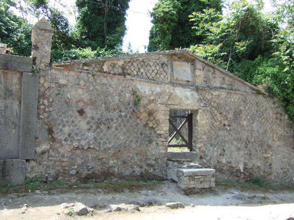 HGW23 Pompeii. May 2006. Front and entrance, looking west.
According to Soprano 
It was the only funeral triclinium so far found in Pompeii. It is located in a small open space which can be accessed from the via dei Sepolcri. The entrance door, m. 1.23 and wide m. 1.05, was surmounted by a pediment with inscriptions that make known the name of the builder of the triclinium, the freedman Callisto, and the person to whom it was dedicated; Cn. Vibio Saturnino.
See Soprano, P. 1950. I triclini allaperto di Pompei. (In Pompeiana, raccolta di studi per il secondo centenario degli scavi di Pompei. Napoli, Gaetano Macchiaroli, Editore, p.304, no.21.
In April 1790 the inscription GABINIG. was found on the wall to the right of the entrance [CIL IV 87].
See Kockel V., 1983. Die Grabbauten vor dem Herkulaner Tor in Pompeji. Mainz: von Zabern. (p. 109).
From PAH, addendum, p.133  
La Vega 99. In April 1790 a ditch was made at the marked location because of rain water, and on the wall there were the following characters, 2  Pal high, and which later by the ancients had been whitewashed, and they are GABINIG ....... The ditch was filled, and the inscription remains where it was seen.
See Fiorelli G., 1860. Pompeianarum antiquitatum historia, Vol. 1: 1748 - 1818, Naples, addendum p. 133.
